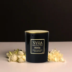 a black container with gold lid next to white flowers