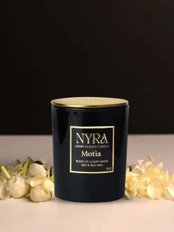 a black container with gold lid next to white flowers