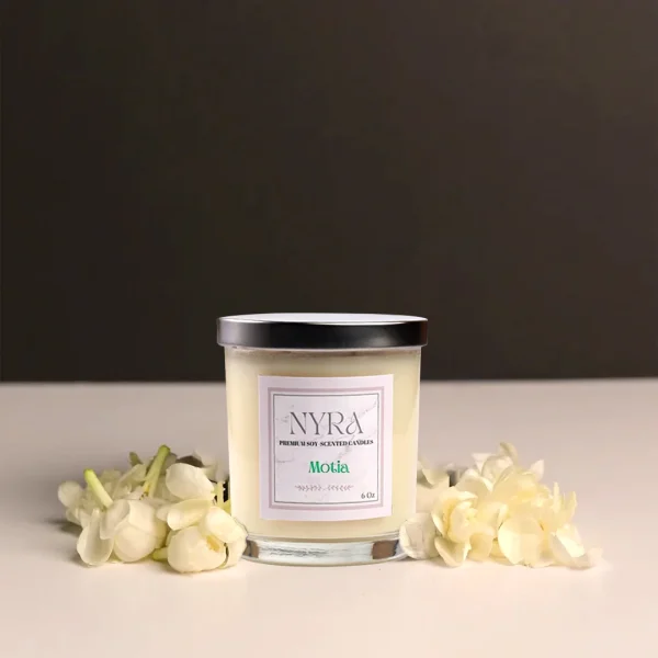 a candle in a jar next to white flowers