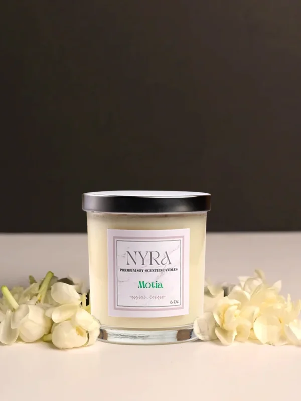 a candle in a jar next to white flowers
