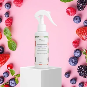 a spray bottle on a white cube surrounded by berries