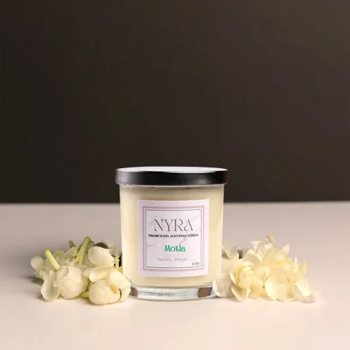 a candle in a jar next to white flowers